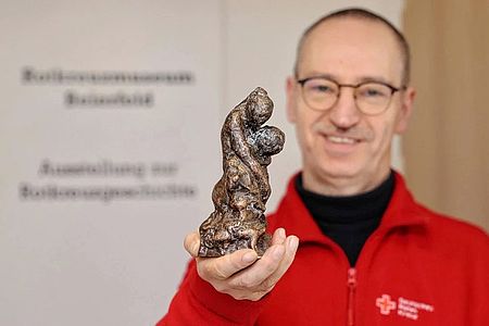 André Uebe zeigt den erstmals ausgereichten Castiglione-Preis des DRK. Eine gegossene Bronzeskulptur, die eine Frau zeigt, die einen Kranken stützt. Bild: Carsten Wagner